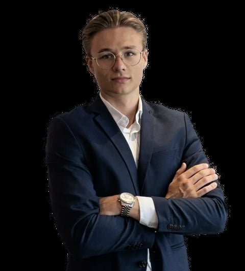 Professional man in dark blue suit and glasses with arms crossed against black background